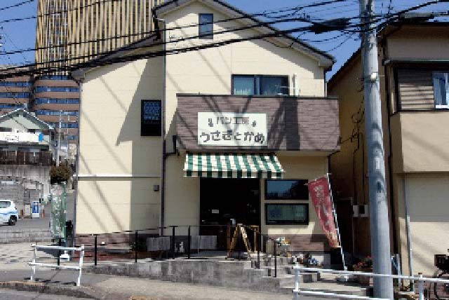 クリーム色と茶色の壁の建物で、「うさぎとかめ」の看板が目印です。